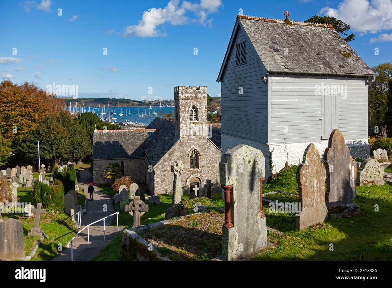 Blick auf die Küstengewässer über das Dach und den Turm der Parish Coastal Church of St Mylor in Cornwall, Großbritannien Stockfoto