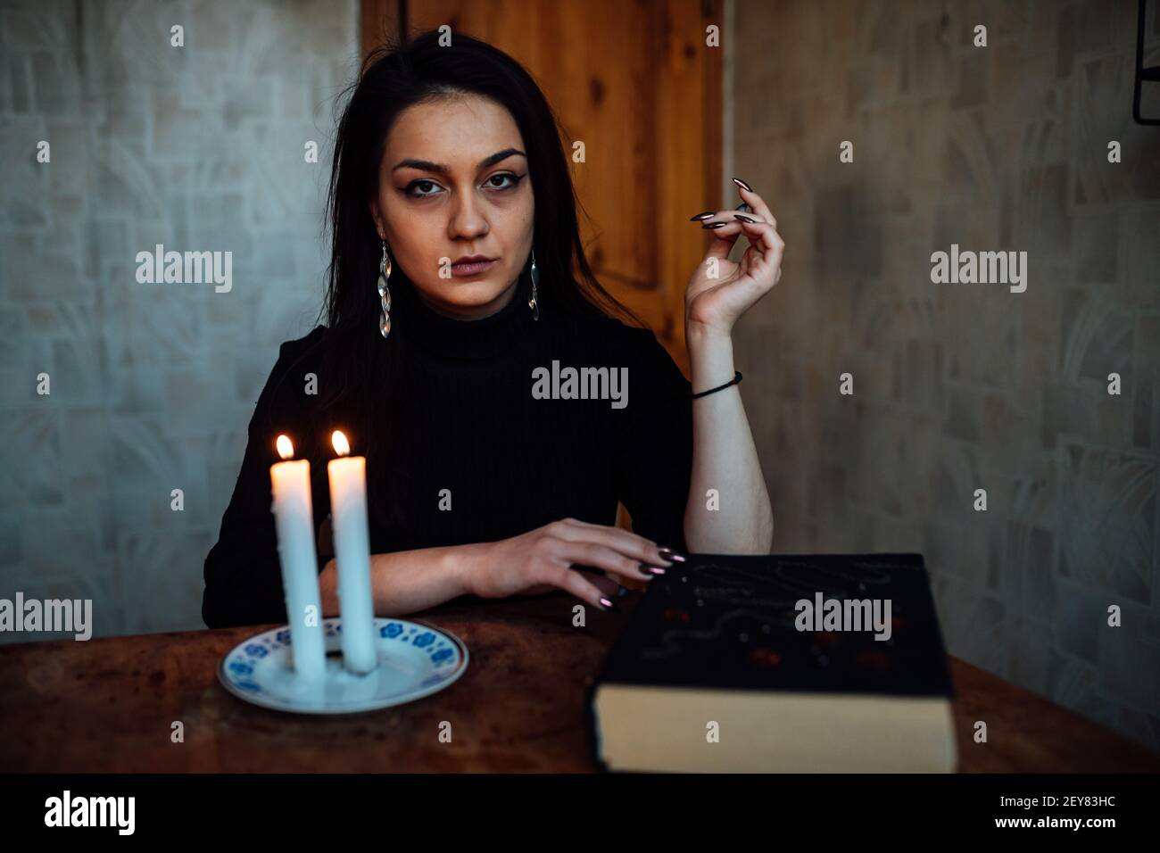 Ein Mädchen Wahrsager zündet Kerzen an, um die Zukunft vorherzusagen. Mystisches Ritual der Kommunikation mit Geistern Stockfoto
