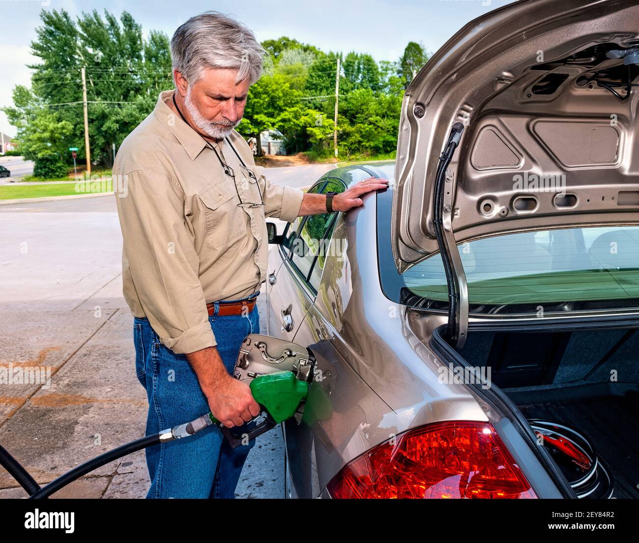 Horizontale Aufnahme eines wütenden älteren Mannes, der Gas pumpt, während die Kraftstoffpreise steigen. Dies ist ein überarbeitetes Bild. Stockfoto
