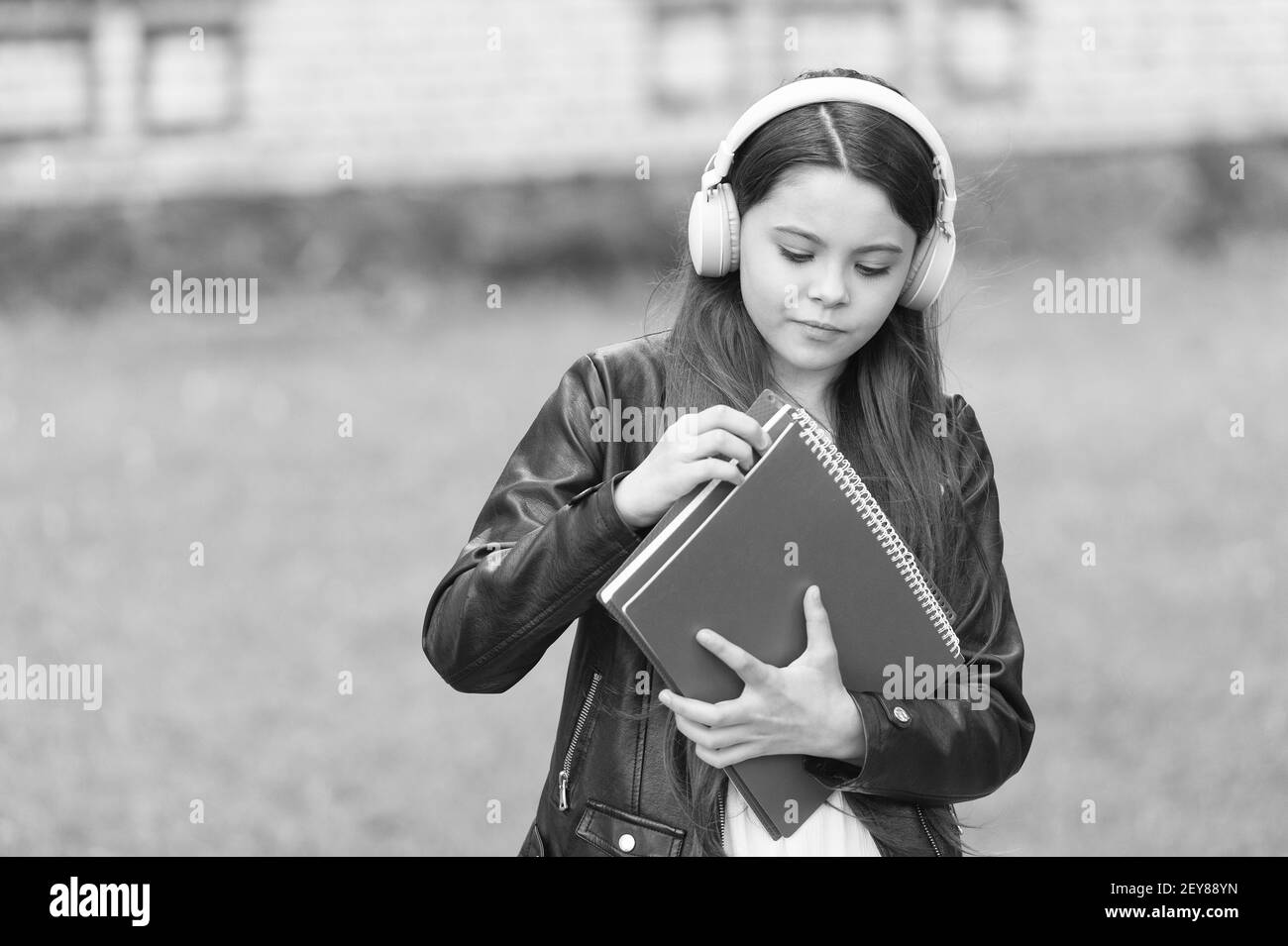 Schulmädchen hören Hörbücher auf dem Weg zur Schule, einfaches Lernkonzept. Stockfoto