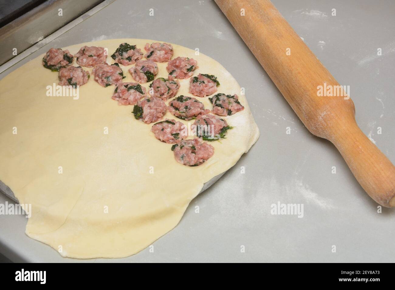 Prozess der Herstellung von hausgemachten Knödel in besonderer Form. Weißer Mehlteig und Hackfleisch mit Spinat. Kochen von Speisen. Stockfoto