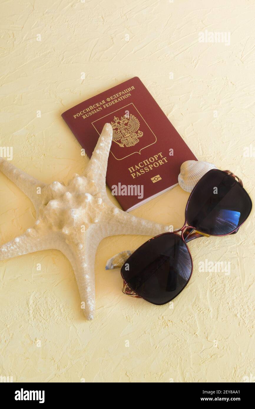 Reisepass, Sonnenbrille und Seestern auf gelbem Hintergrund. Strandurlaub Konzept, Abreise aus dem Land. Stockfoto