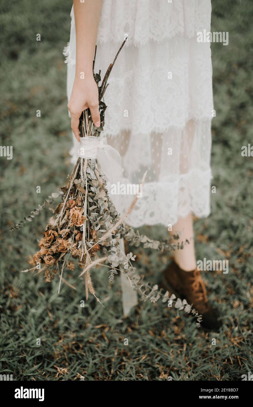 Ein Brautstrauß mit trockenen Blumen in der Hand einer Braut; Boho Stil Hochzeit Stockfoto