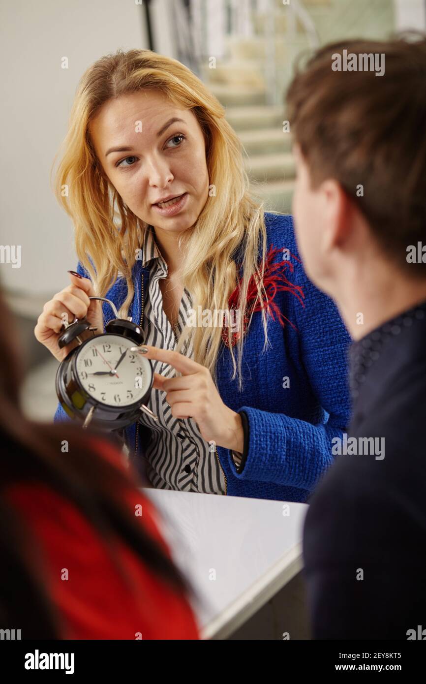Eine verärgerte weibliche Chefin zeigt eine Zeit auf einen Untergebenen Stockfoto