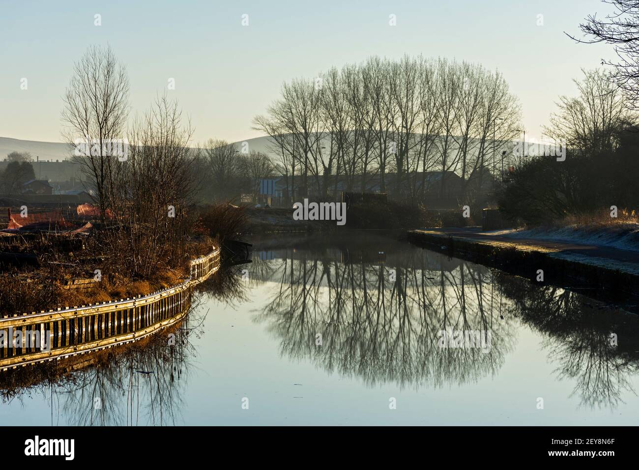 Bäume spiegeln sich im Ashton-Kanal mit den Pennine-Hügeln dahinter, in Droylsden, Tameside, Manchester, Großbritannien Stockfoto