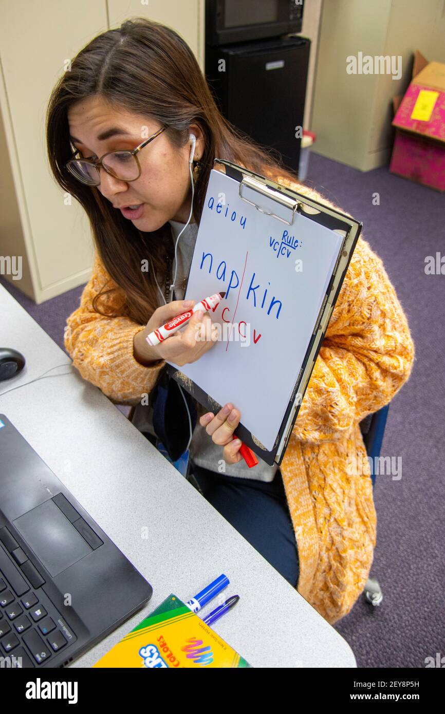 Eine kalifornische Grundschullehrerin hält ein geschriebenes Blatt des zweisilbigen Wortes "Serviette" hoch und erklärt Vokale und Konsonanten für ein Schülerwesen Stockfoto