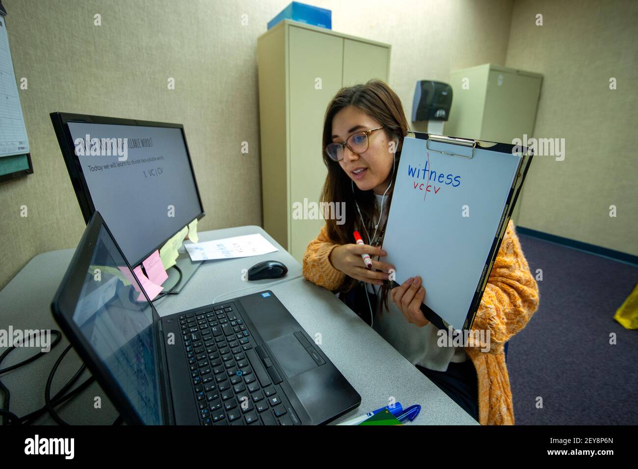 Eine kalifornische Grundschullehrerin hält ein geschriebenes Blatt des zweisilbigen Wortes "Zeuge" hoch und erklärt Vokale und Konsonanten für ein Schülerwesen Stockfoto
