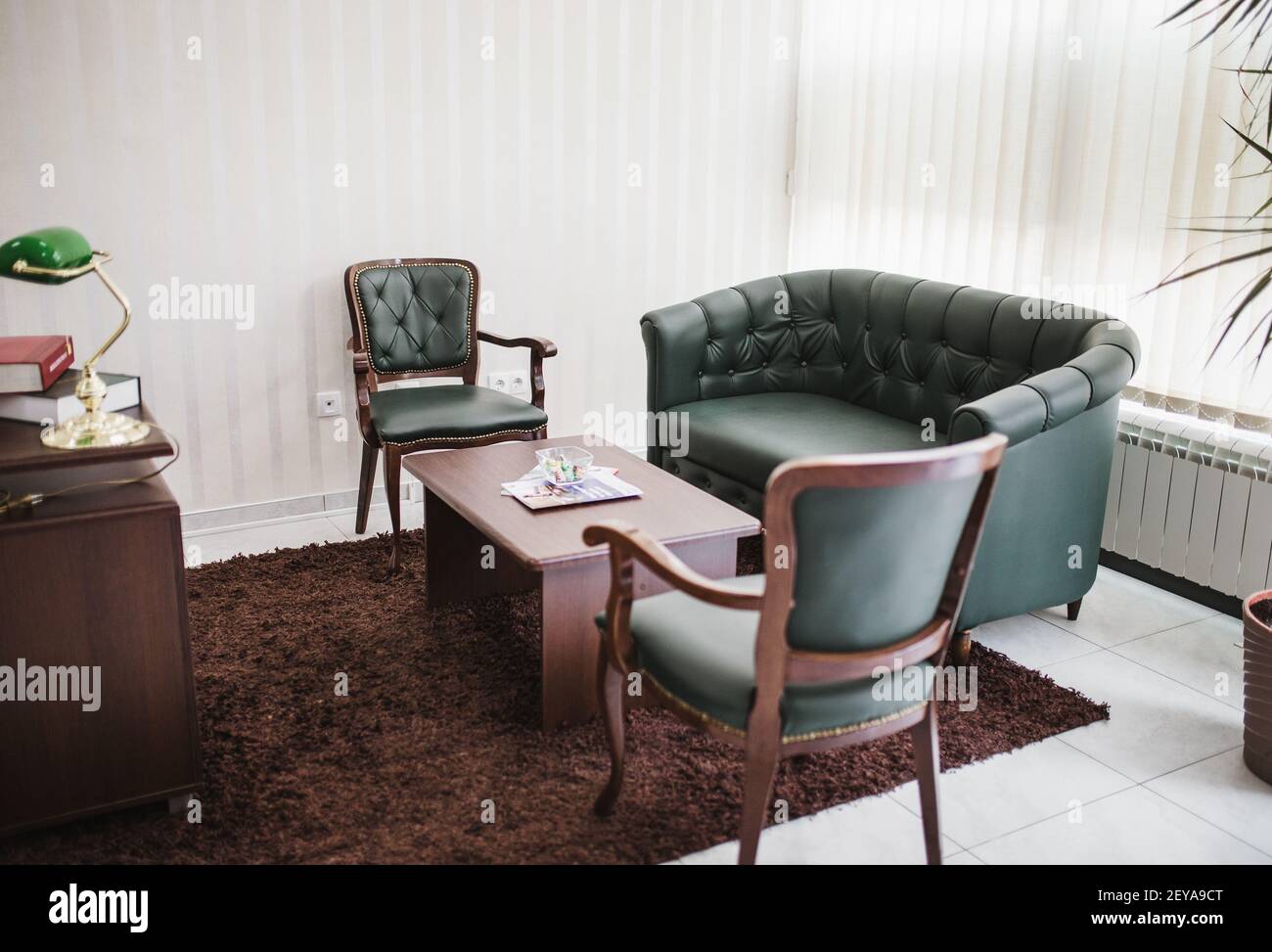Das schöne luxuriöse und moderne grüne Ledersofa mit Stühlen Und einen Tisch im Büro Stockfoto
