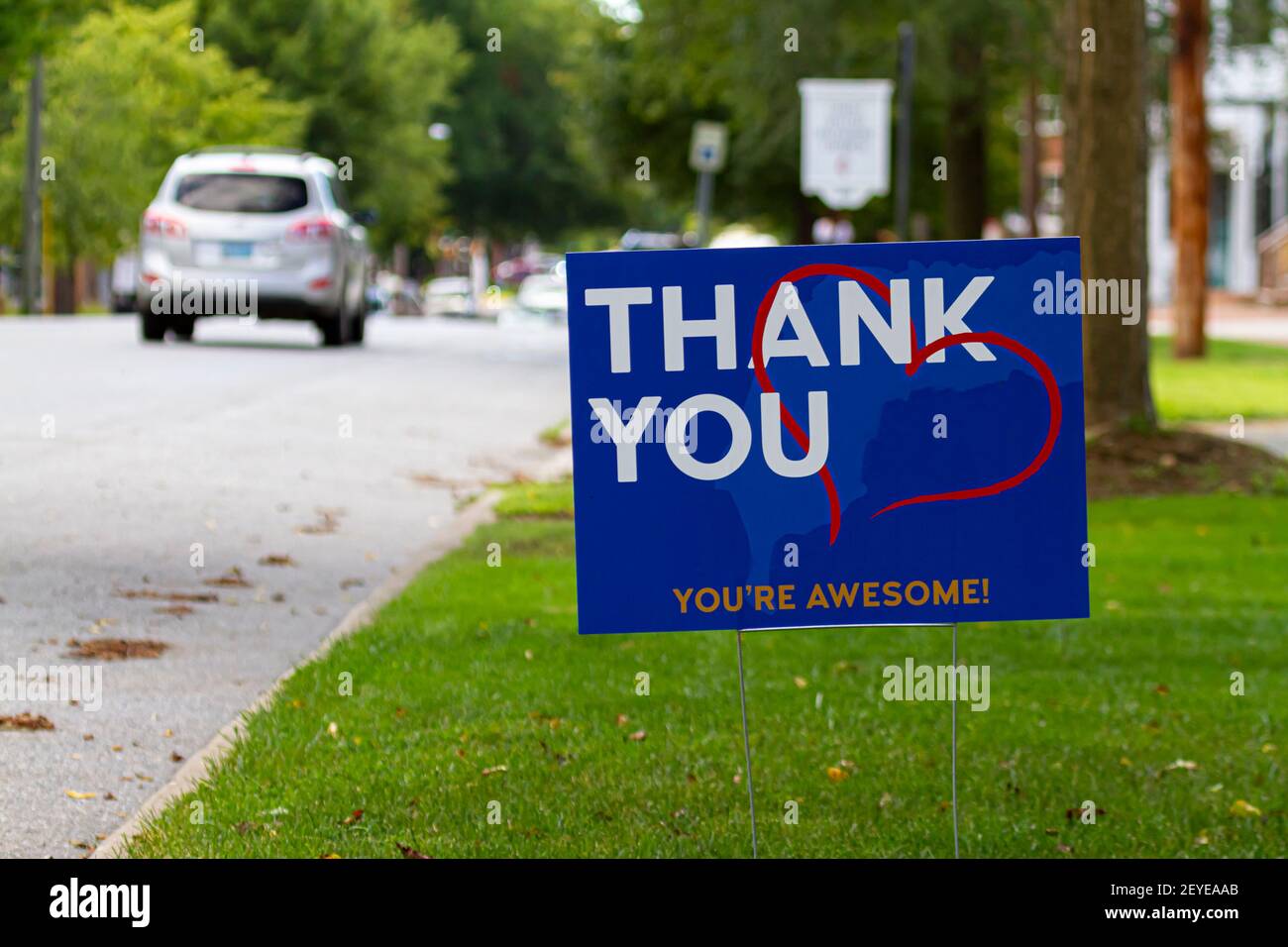 Ein Yard-Schild an der Straße mit der Aufschrift "Danke, du bist genial" in weißem und orangefarbenem Text auf blauem Hintergrund. Ein rotes Herz-Symbol ist eingebettet. Anpassbare Ve Stockfoto