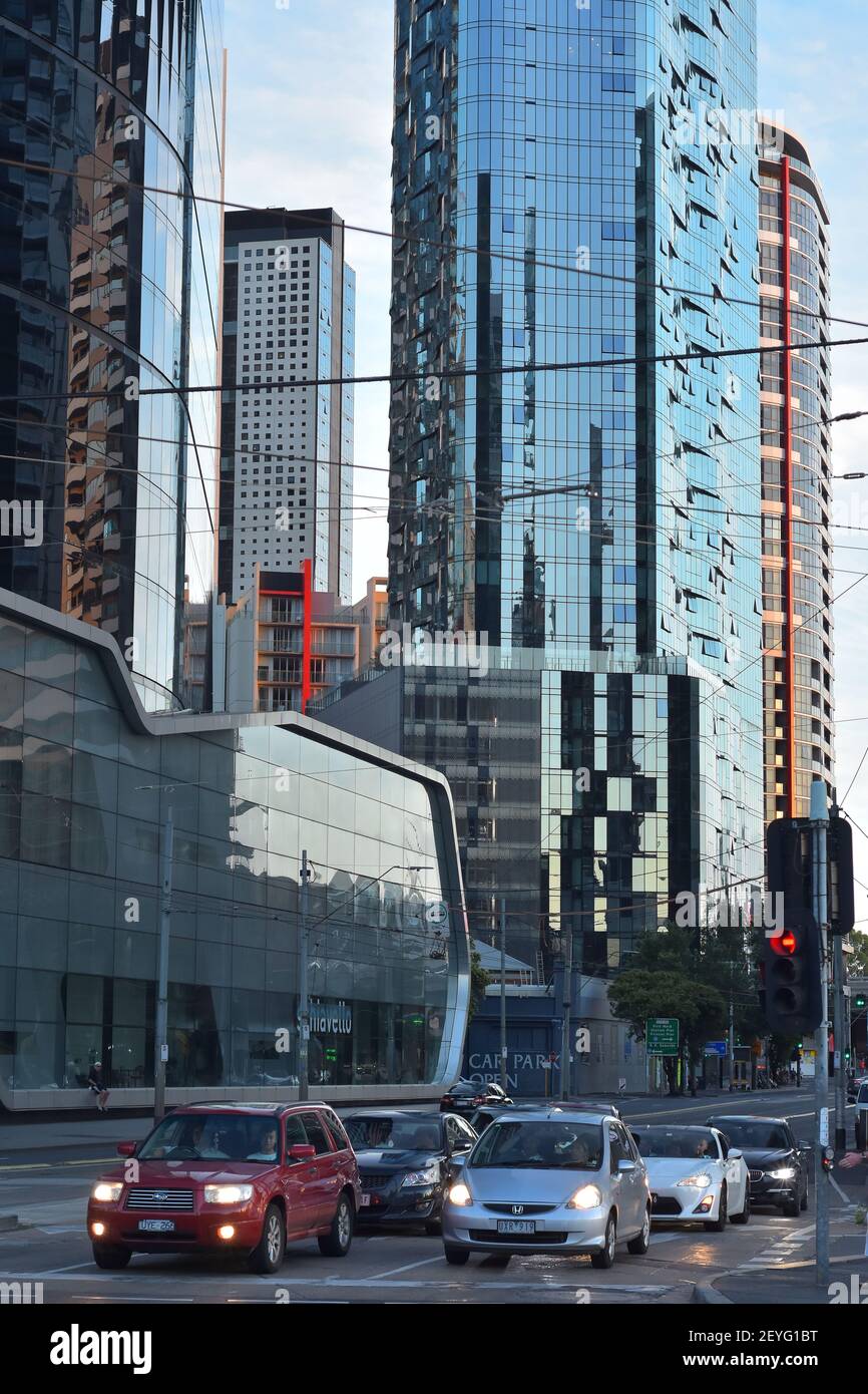 Die Autos hielten an der roten Ampel an der Kreuzung mit hohen Gebäuden mit Glaswänden im Hintergrund. Stockfoto