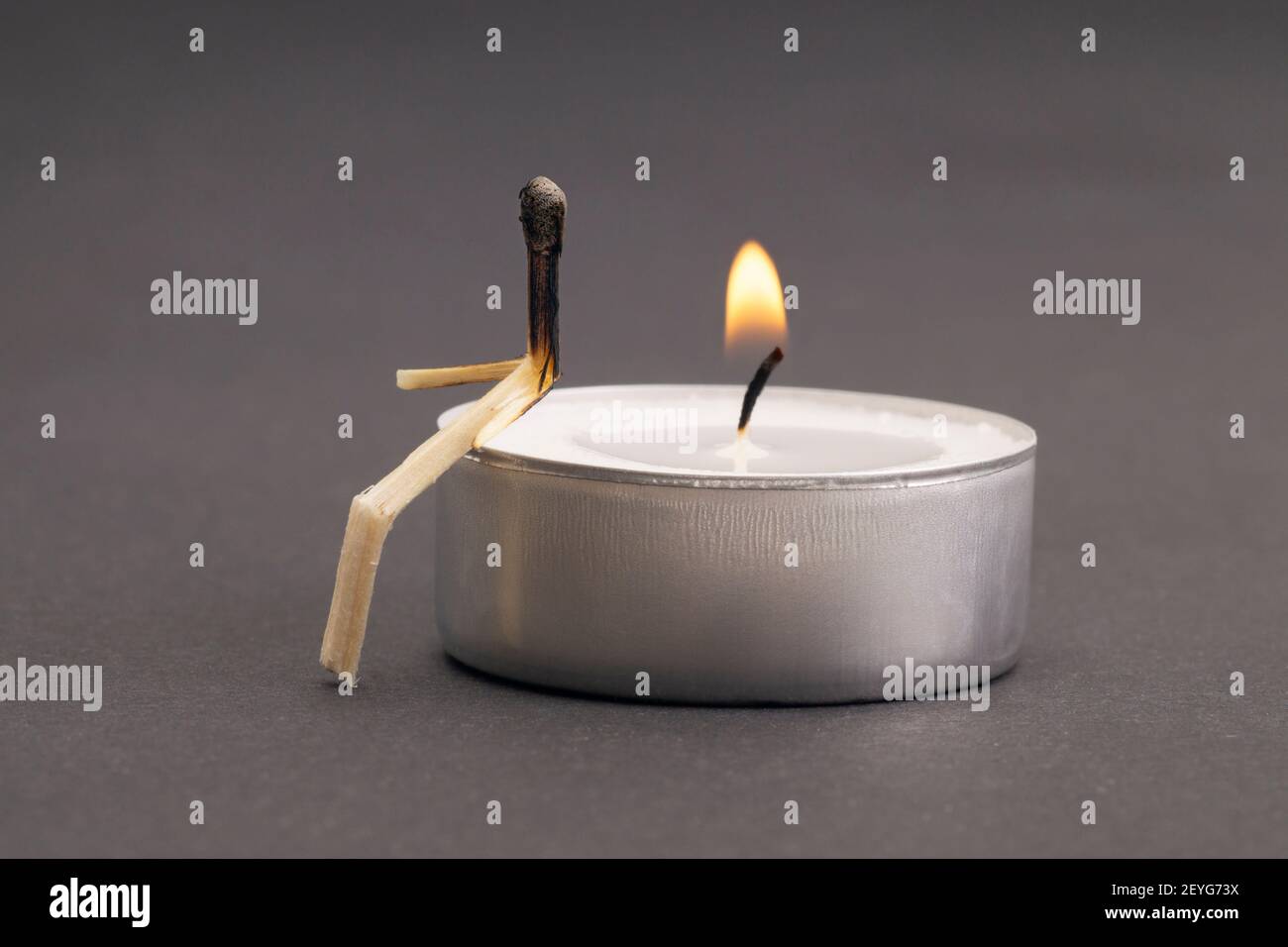 Matchstick-Charakter sitzt auf einer brennenden Teelkerze. Unerfülltes Liebeskonzept. Stockfoto