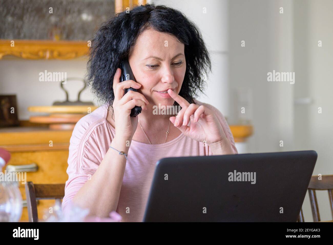 Frau am Telefon Frau am Telefon Während der Arbeit am Computer Stockfoto