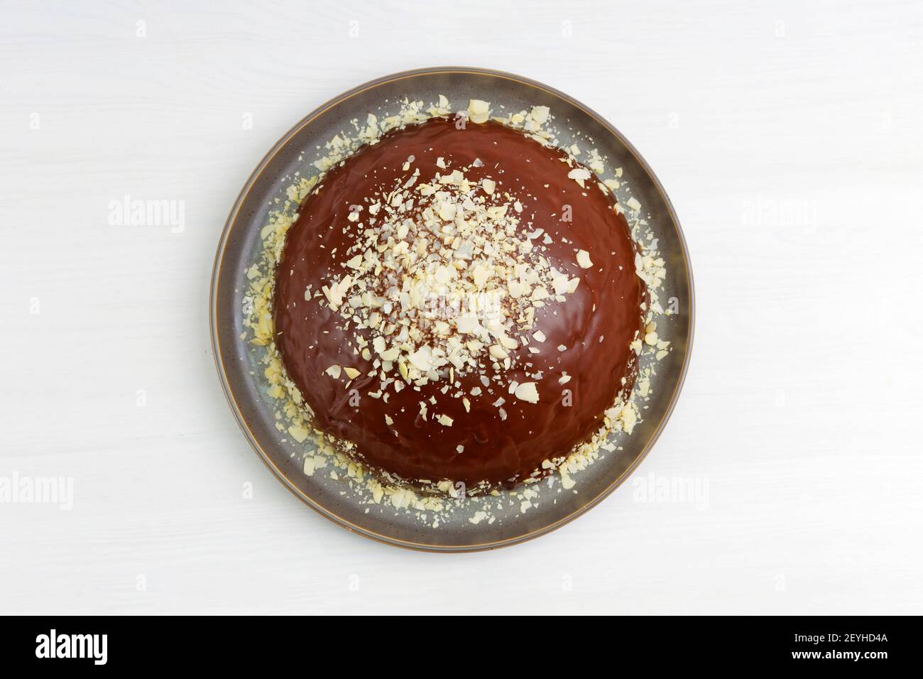 Hausgemachter Schokoladenkäsekuchen mit Mandelscheiben auf weißem Holztisch. Draufsicht. Stockfoto