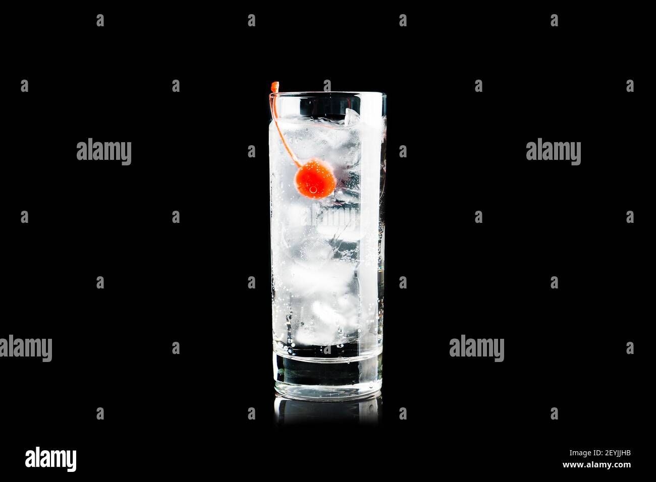 Bitter transparent Cocktail mit Cocktail-Kirsche isoliert auf schwarzem Hintergrund. Selektiver Fokus. Geringe Schärfentiefe. Stockfoto