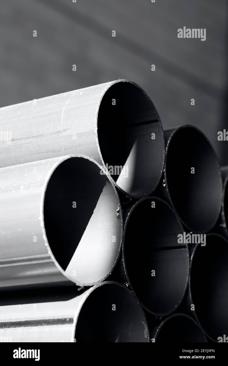 Rohre aus Eisen im Lager gestapelt, industriellen Hintergrund in schwarz und weiß Stockfoto
