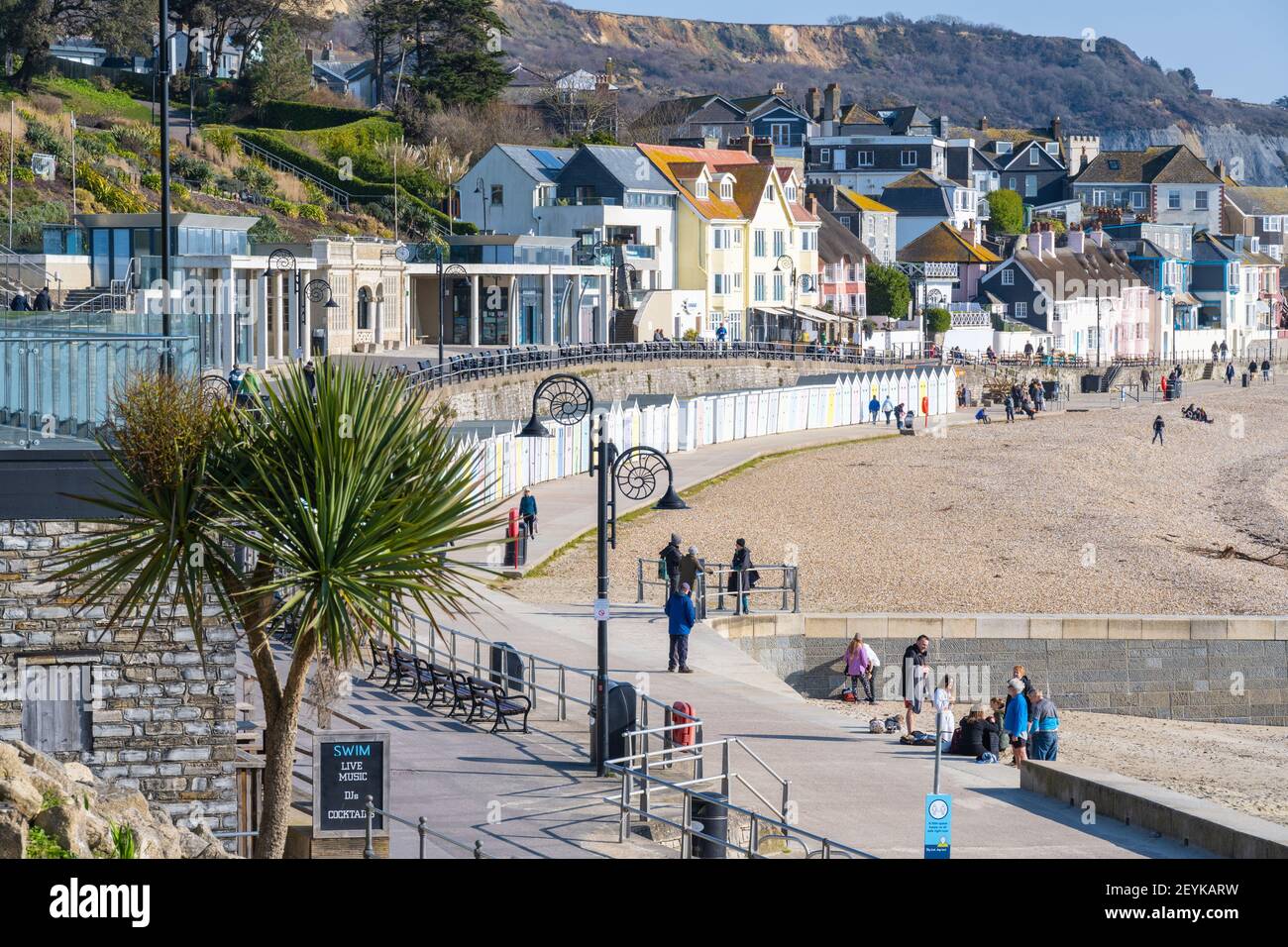 Lyme Regis, Dorset, Großbritannien. März 2021, 6th. UK Wetter: Die Menschen genießen einen kühlen Spaziergang entlang der Küste bei Lyme Regis an einem Morgen von knackigen, hellen Sonnenschein und klaren blauen Himmel. Kredit: Celia McMahon/Alamy Live Nachrichten Stockfoto