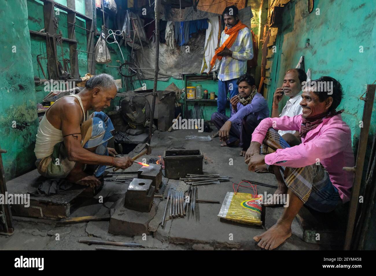 Kolkata, Indien - Februar 2021: Ein Mann, der in seiner Schmiedewerkstatt arbeitet, während seine Kunden am 5. Februar 2021 in Kolkata, Westbengalen, Indien warten. Stockfoto