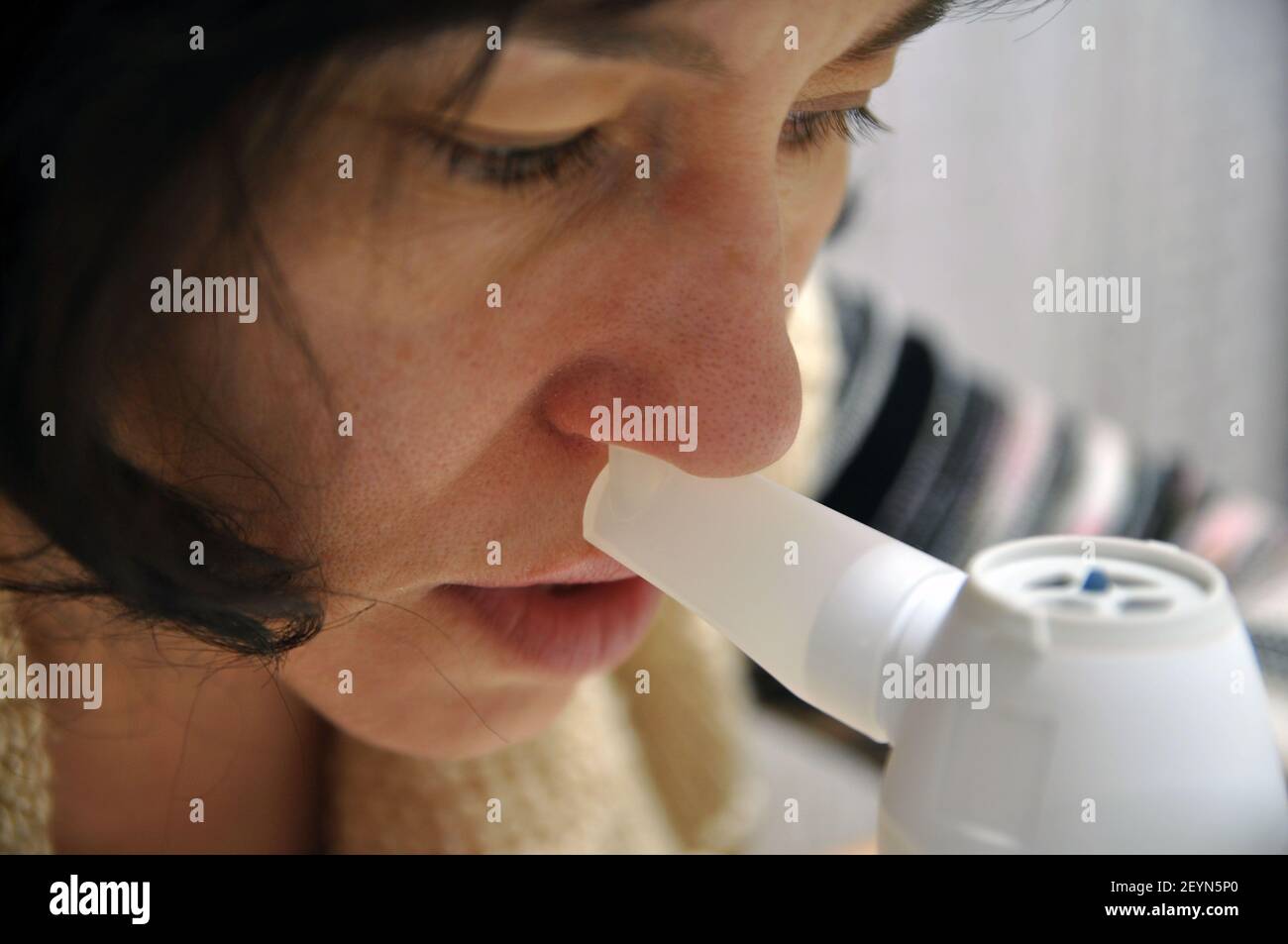 Eine Frau mit einer Erkältung inhaliert durch die Nase. Inhalator, Frau hält Inhalationsschlauch in der Nase. Stockfoto