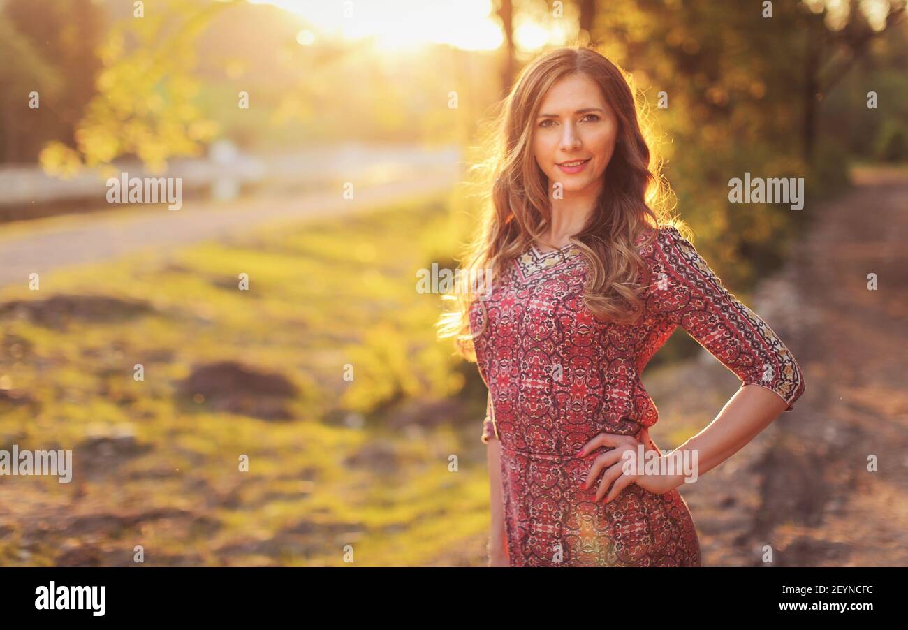 Porträt der jungen Frau in lässigen Sommerkleid, starke Sonnenuntergang Hintergrundbeleuchtung mit schönen Bokeh Stockfoto