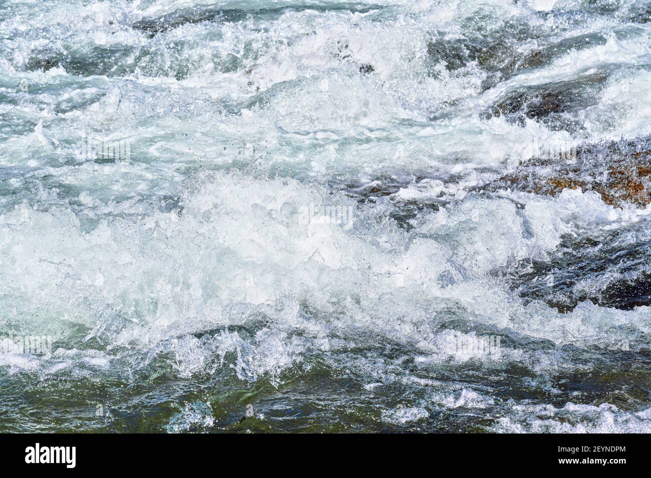 Schnelle Quelle Fluss über Felsen an sonnigen Tag, bilden weiße Wasserwellen, Nahaufnahme Detail - abstrakte Natur Hintergrund Stockfoto