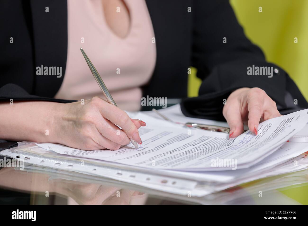 Eine im Büro arbeitende Direktorin sitzt am Tisch und unterschreibt Dokumente. Nahaufnahme. Stockfoto