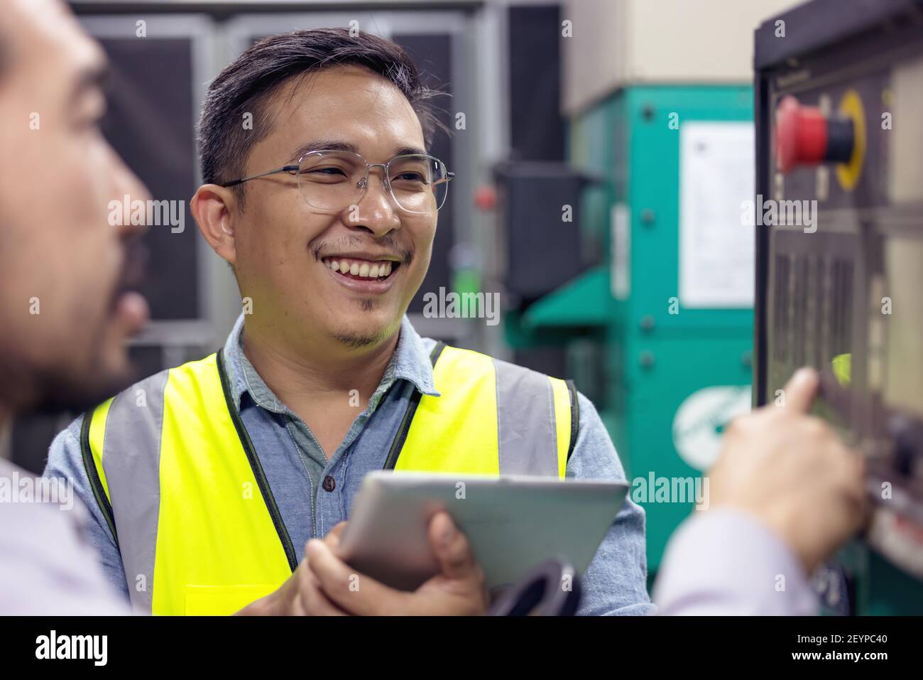 Nahaufnahme des Technikers oder Elektrikers, der arbeitet, prüfen Sie das elektrische System mit dem Tablet im Werk. Stockfoto
