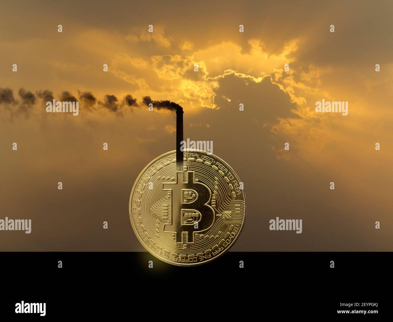 Ein rauchender Industriekamin, der Teil eines Bitcoin-Tokens ist Gegen einen dramatischen orangefarbenen Himmel, der den Stromverbrauch von veranschaulicht Kryptowährung Stockfoto