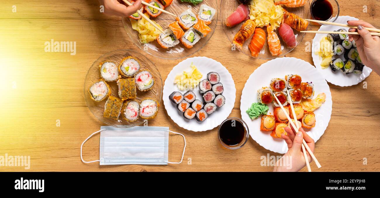 Banner. Lockdown Home Dinner Party in Pandemie mit japanischem Sushi von Lieferung oder Take-away Service. Verschiedene Lachs, Krabben, vegane Brötchen, Wasabi Stockfoto
