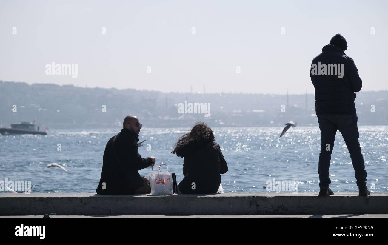 Türkei. Bosporus istanbul. Menschen, Touristen sitzen auf Betonstein in Ufer bosporus. Sie fotografieren und füttern Möwen und Tauben und Tauben Stockfoto