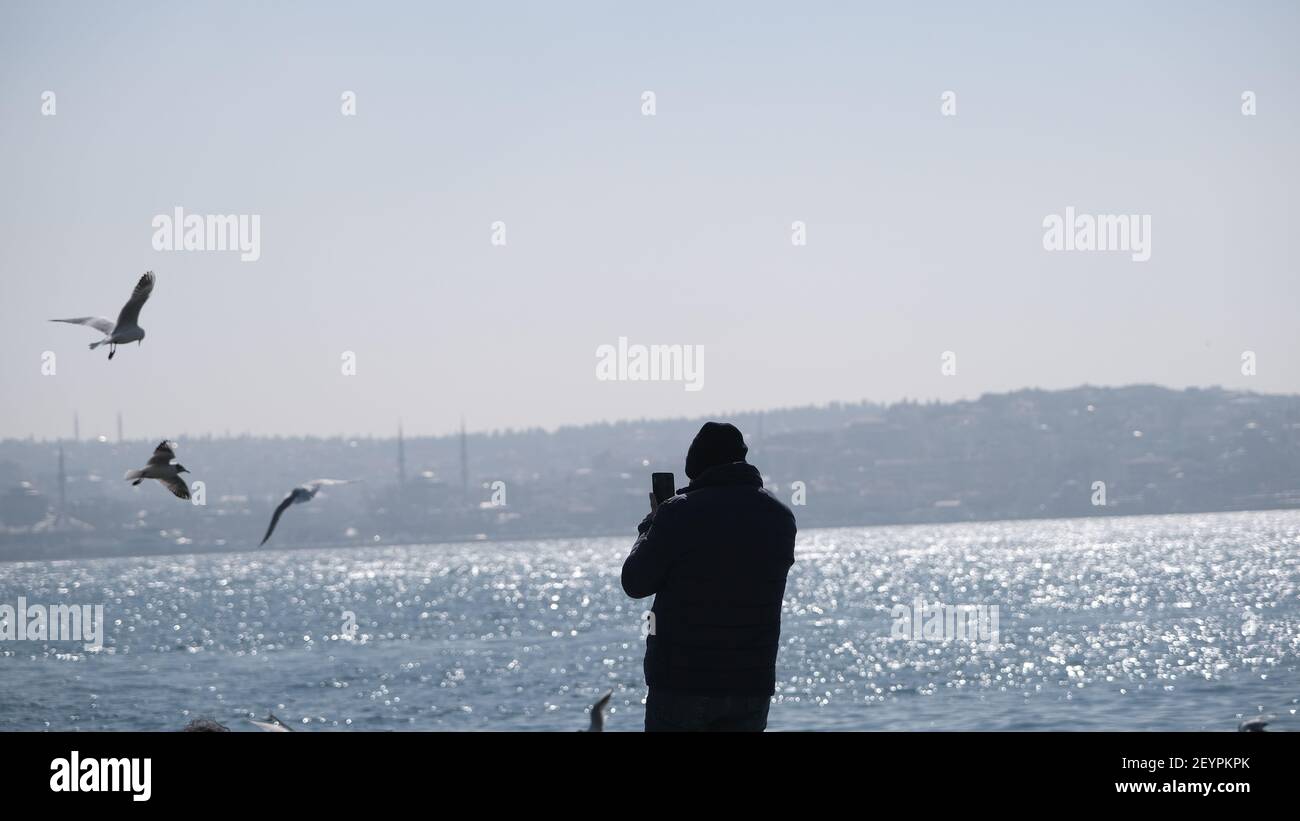 Türkei. Bosporus istanbul. Menschen, Touristen sitzen auf Betonstein in Ufer bosporus. Sie fotografieren und füttern Möwen und Tauben und Tauben Stockfoto