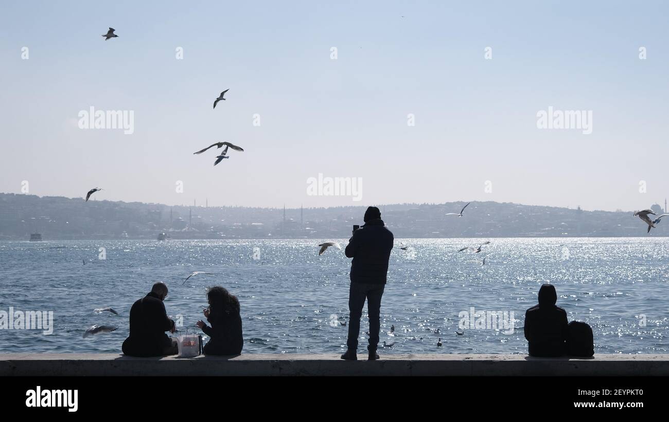 Türkei. Bosporus istanbul. Menschen, Touristen sitzen auf Betonstein in Ufer bosporus. Sie fotografieren und füttern Möwen und Tauben und Tauben Stockfoto