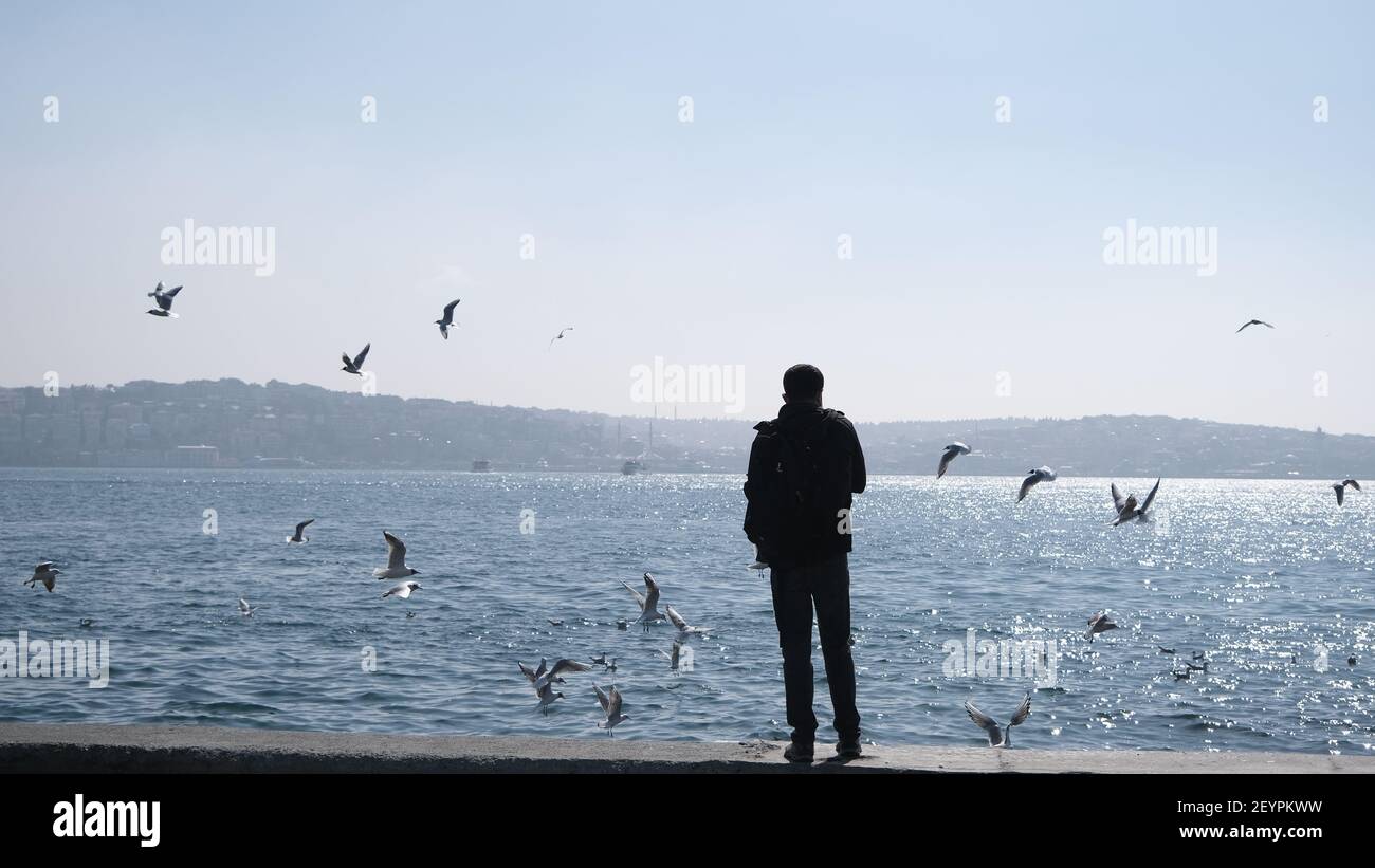 Türkei. Bosporus istanbul. Menschen, Touristen sitzen auf Betonstein in Ufer bosporus. Sie fotografieren und füttern Möwen und Tauben und Tauben Stockfoto
