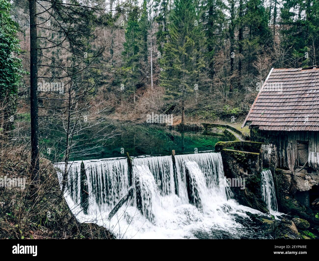 Eine schöne Aufnahme eines alten Holzhauses daneben Ein Wasserfall in Stockfoto