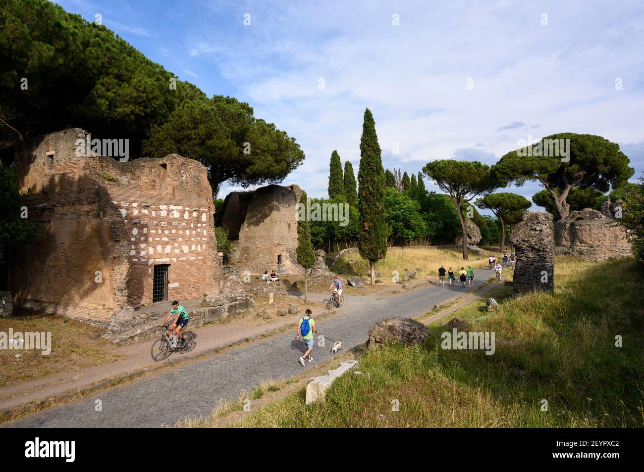 Rom Italien. Via Appia Antica (Appian Way), Menschen zu Fuß und mit dem Fahrrad zwischen alten römischen Grabdenkmälern. L-R; Primo Monumento in Lateriz Stockfoto