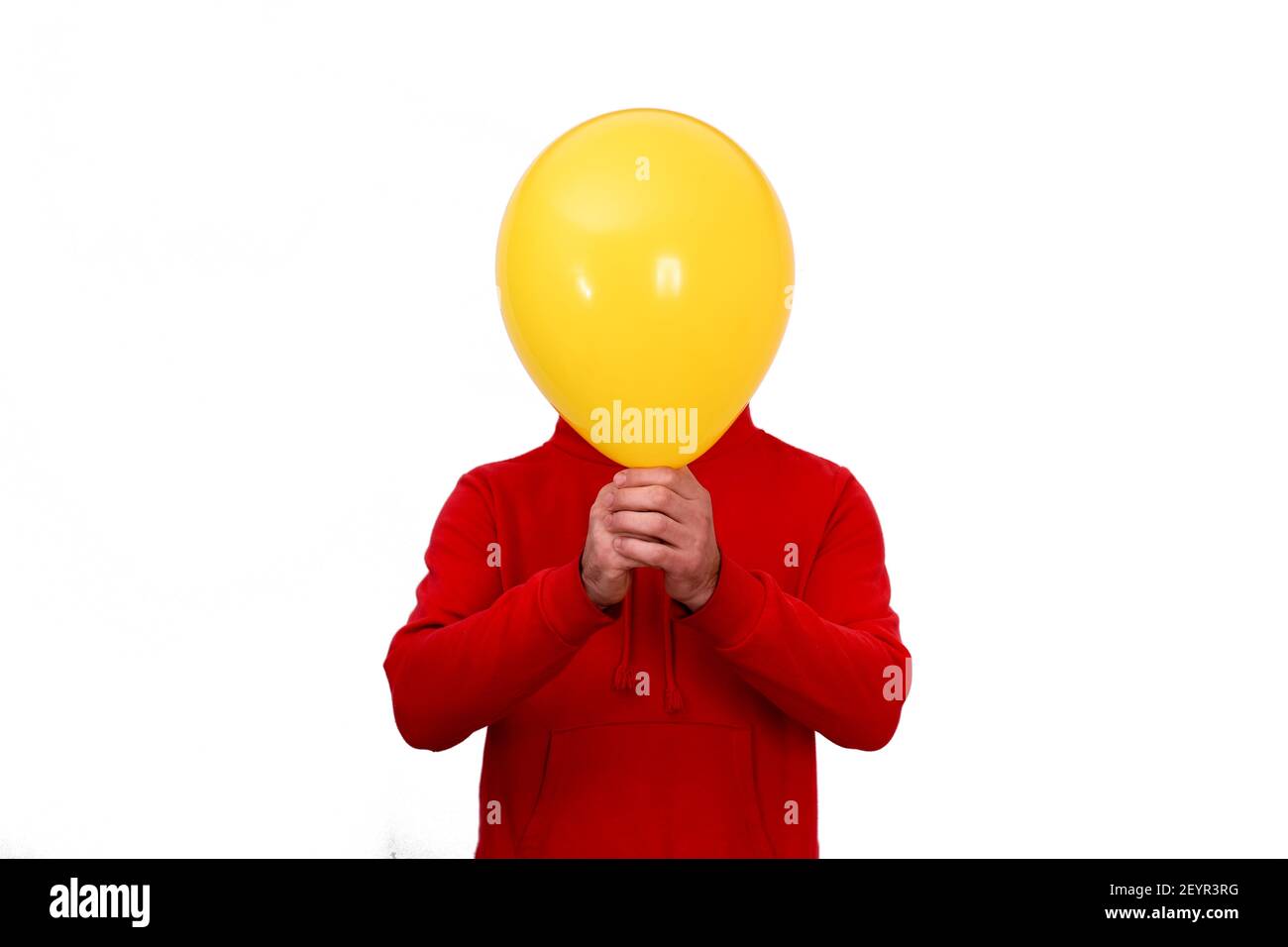 Ein Mann bedeckt sein Gesicht mit einem gelben Ballon. Stockfoto