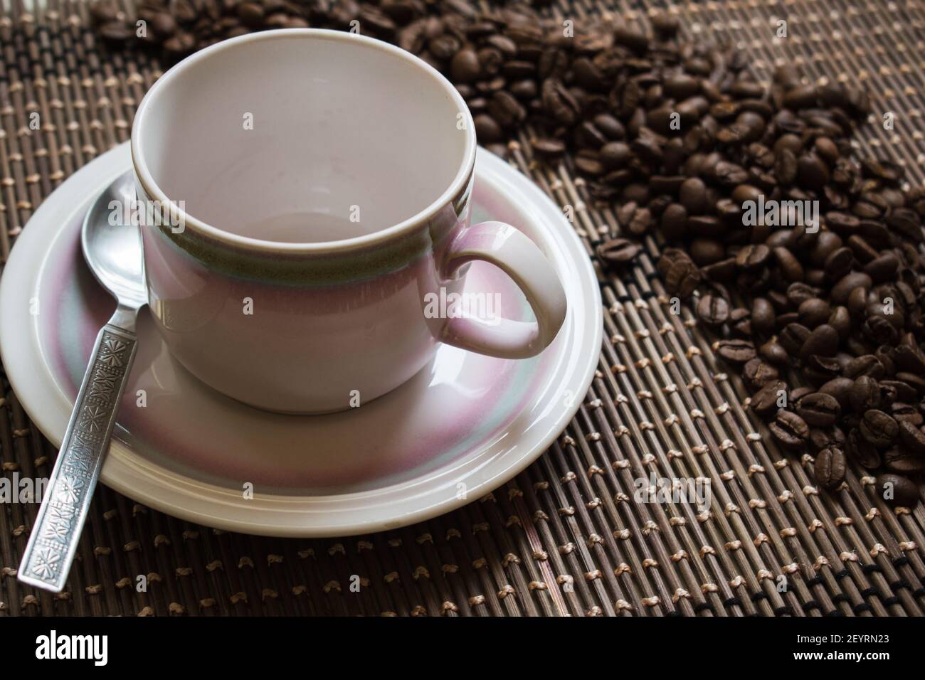 Eine leere Tasse Kaffee und Kaffeebohnen auf einem Bambusmatte Stockfoto