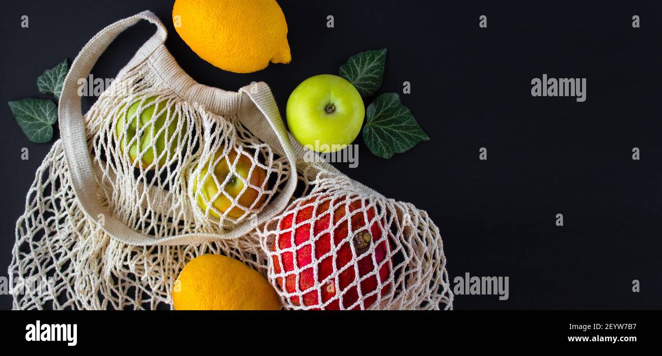 Freundliche Öko wiederverwendbare Beutel mit Früchten. Keine Verschwendung. Nachhaltiges Lifestyle-Konzept Kunststoff frei. Schwarzer Hintergrund Stockfoto