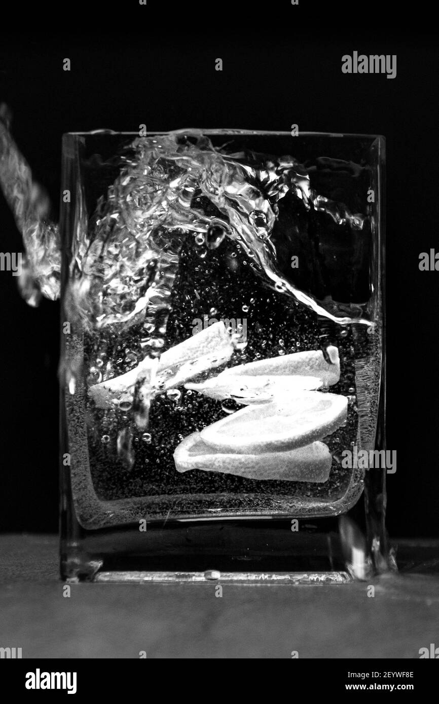 Die Zitrone im Schnitt im Wasser im Glas auf Schwarzer Hintergrund Stockfoto