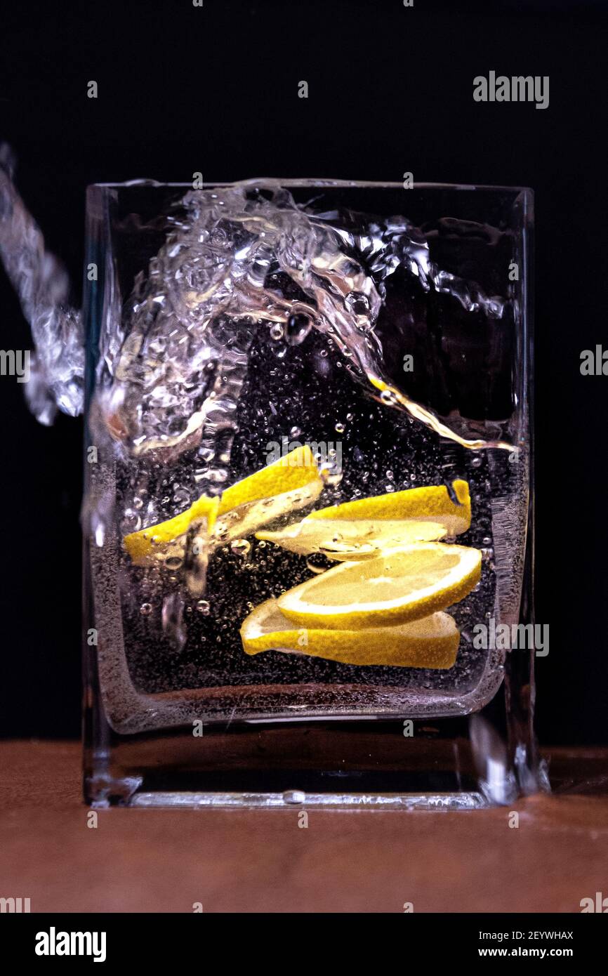 Die Zitrone im Schnitt im Wasser im Glas auf Schwarzer Hintergrund Stockfoto
