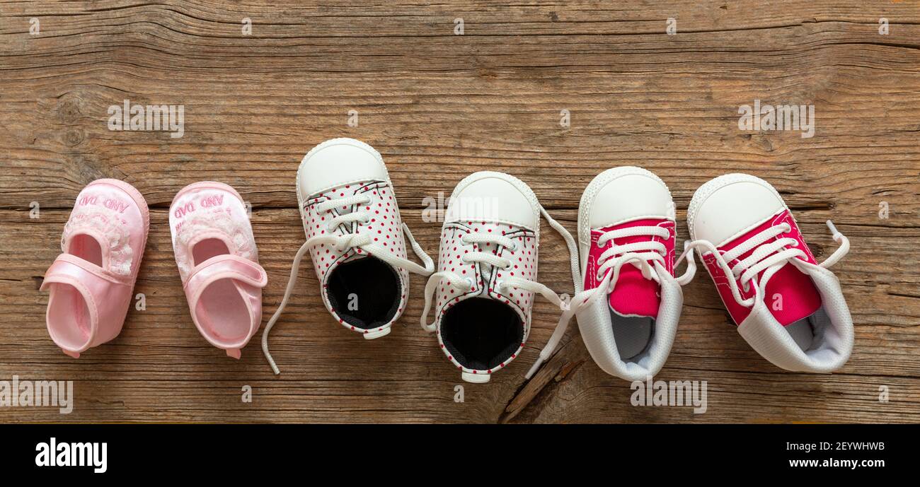 Baby Mädchen erste Schritte. Drei Paare von Neugeborenen Schuhe Vielfalt  auf Holzboden Hintergrund, Draufsicht. Kinderschuhe, Babyschuhe und weiche  Babyschuhe in einer Reihe Stockfotografie - Alamy