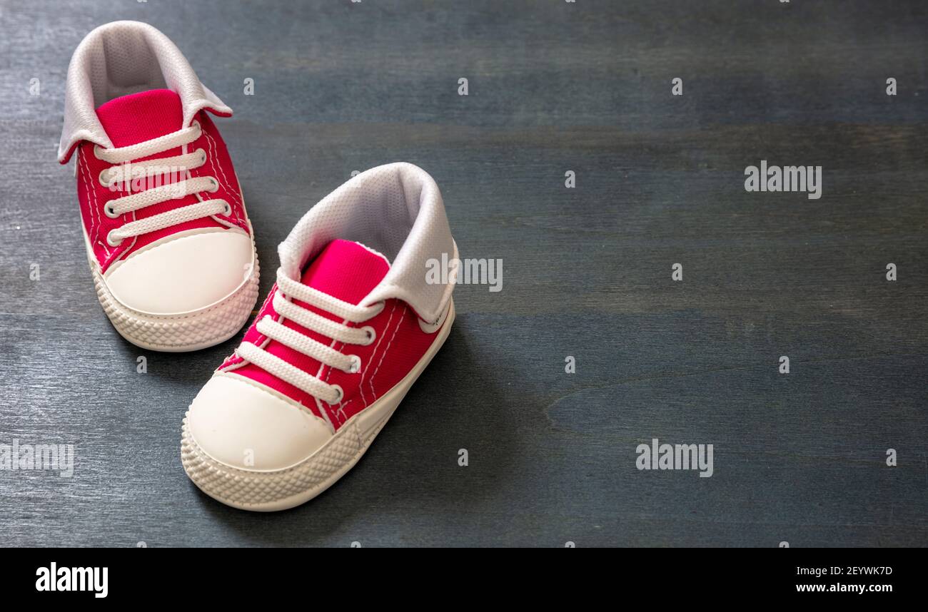 Baby Mädchen Sportschuhe auf blauem Holzboden. Kind kleine Größe rosa Sneakers, Leinwand Booties Nahaufnahme. Platz, Einladungsvorlage für Karten Stockfoto