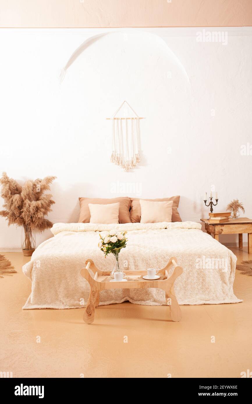 Schönes beigefarbenes weißes Schlafzimmer. Mode-Design, Pampas, Bett Tablett  Tisch Blumen von Pflanzen, Kerzen, Korbteppiche. Möbel diy. Innenfoto  Stockfotografie - Alamy