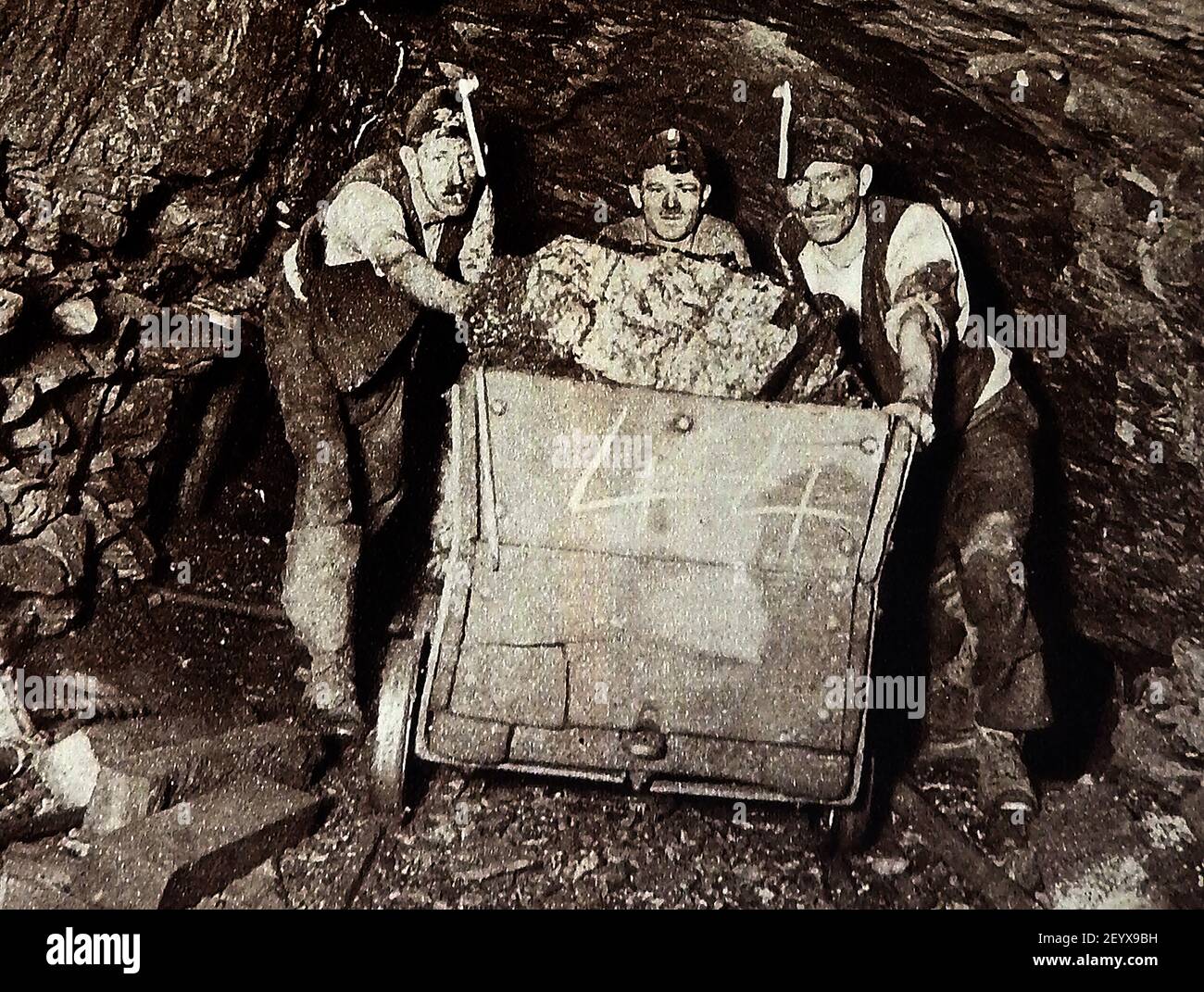 Ein altes Foto (ca. 1940), das Kohlebergarbeiter zeigt, die einen Lastwagen mit Kohle unterirdisch Rollen. Stockfoto