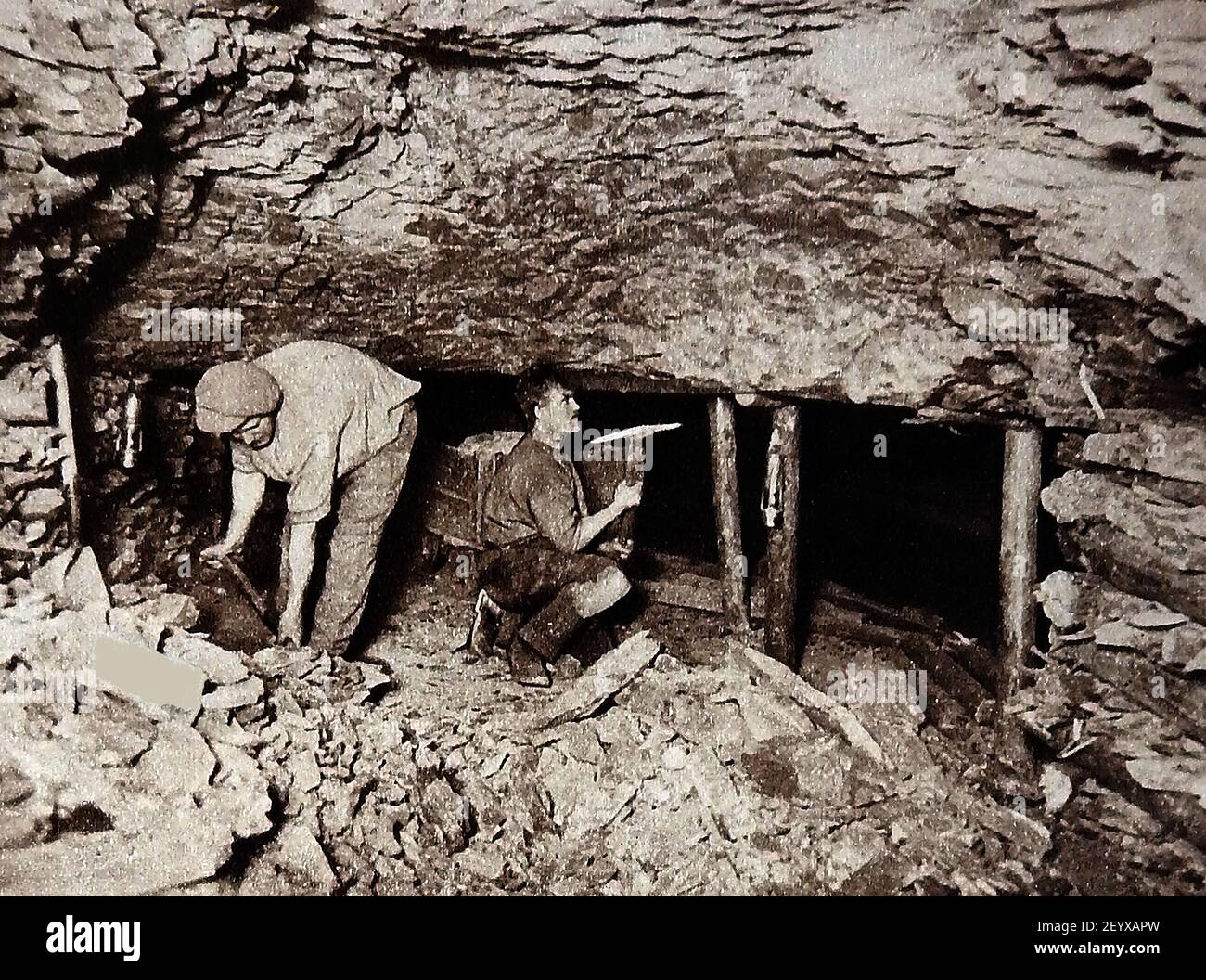 Ein altes Foto (ca. 1940), das Bergarbeiter an der Kohlewand mit Picks, Schaufeln, Grubenrequisiten und Minenlampen zeigt Stockfoto
