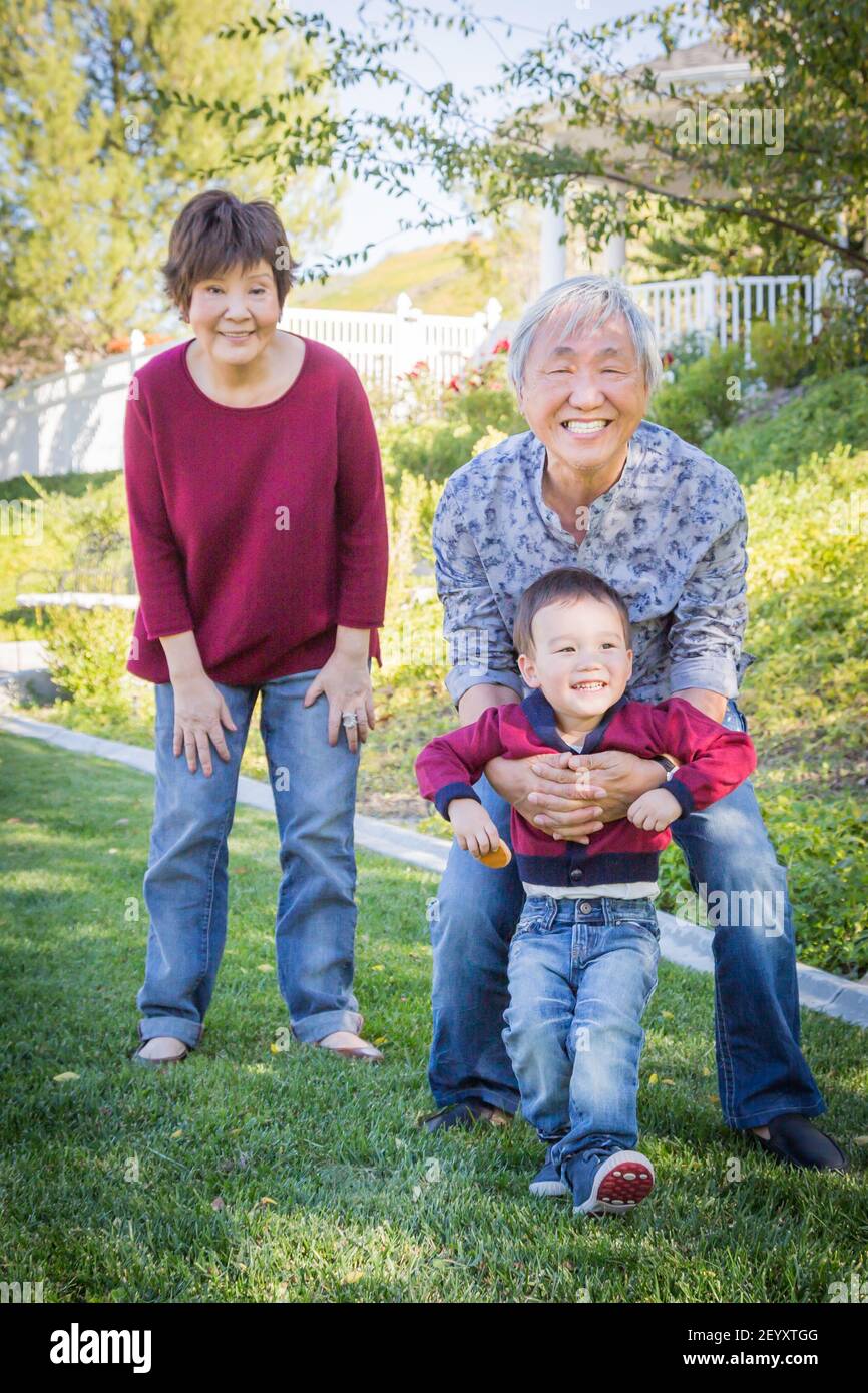 Glücklich chinesischen Großeltern Spaß mit ihren Enkel Mischlinge außerhalb. Stockfoto