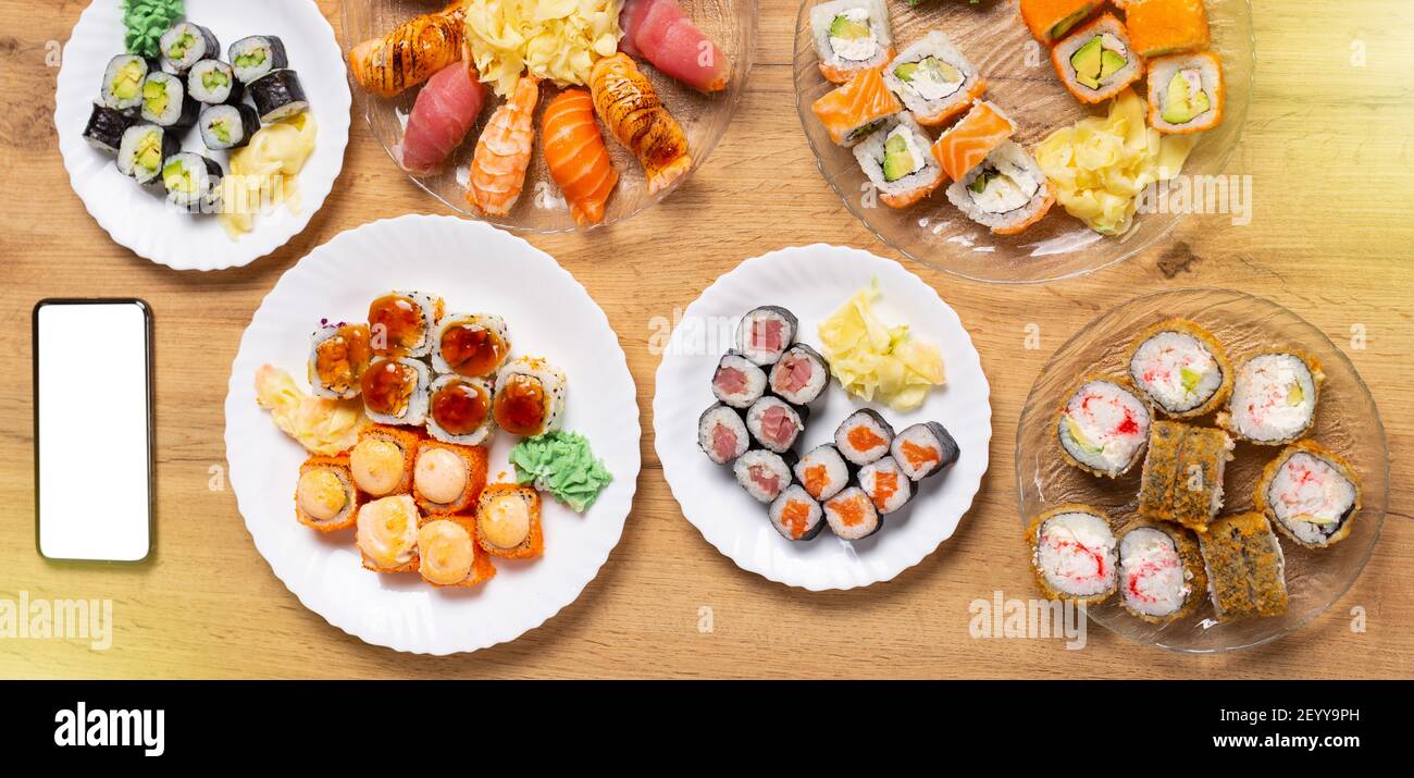 Baner lang Format.Home Dinner-Party, Sushi-Feier, Mock up, leeren Raum Telefon-Bildschirm. Verschiedene Lachs, Krabben, vegane Brötchen, Wasabi, Ingwer auf Stockfoto