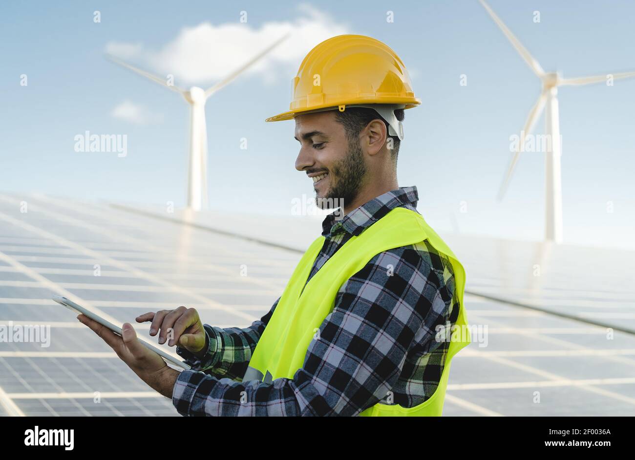 Junge Ingenieur beobachten auf digitalen Tablet den neuen grünen Plan Für alternative Energie mit Windturbine und Solarpanel Stockfoto