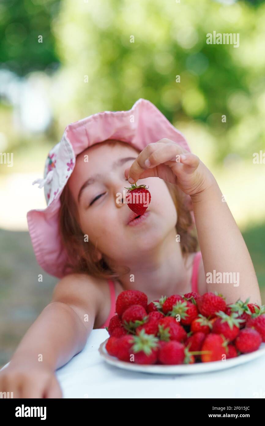 Portrait von Happy cute preteen Mädchen isst Erdbeeren am Sommertag. Weich fokussiert Stockfoto