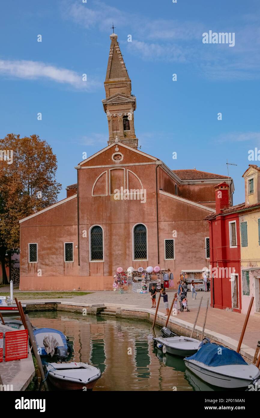 Der schiefe Turm der Kirche San Martino Vescovo, mit bunten venezianischen Häusern entlang des Kanals auf der Insel Burano - Venedig, Venetien, Italien - Sceni Stockfoto