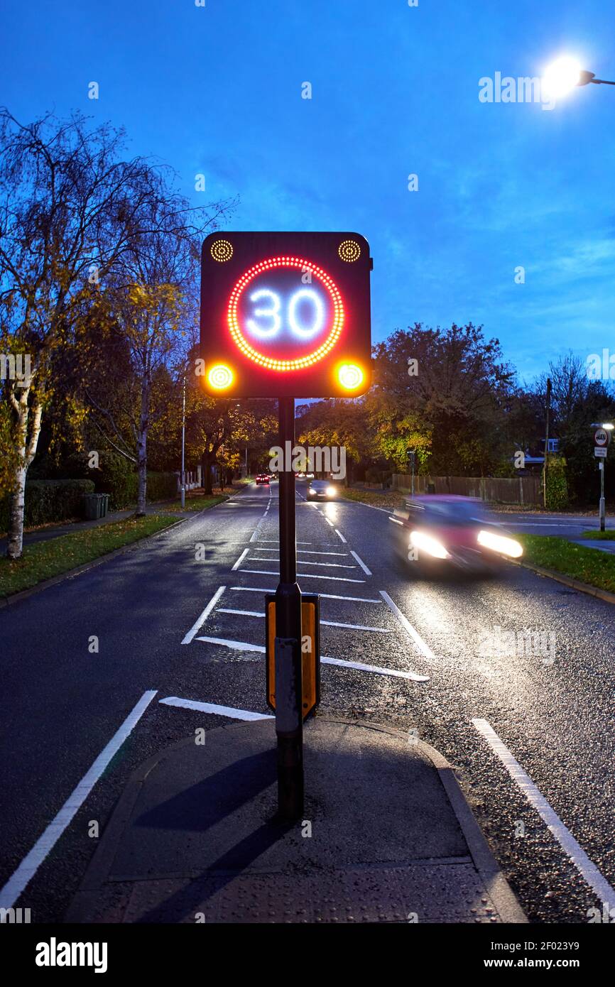 2-Wege-Straße zeigt entgegenkommenden und vorbeifahrenden Verkehr in der Nacht mit einem 30-Meilen-pro-Stunde (mph) elektronische Geschwindigkeitsbegrenzung LED-Schild. Stockfoto